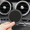A hand holds a black crystal rhinestone non-slip cup mat for cars, positioned in front of a car stereo.