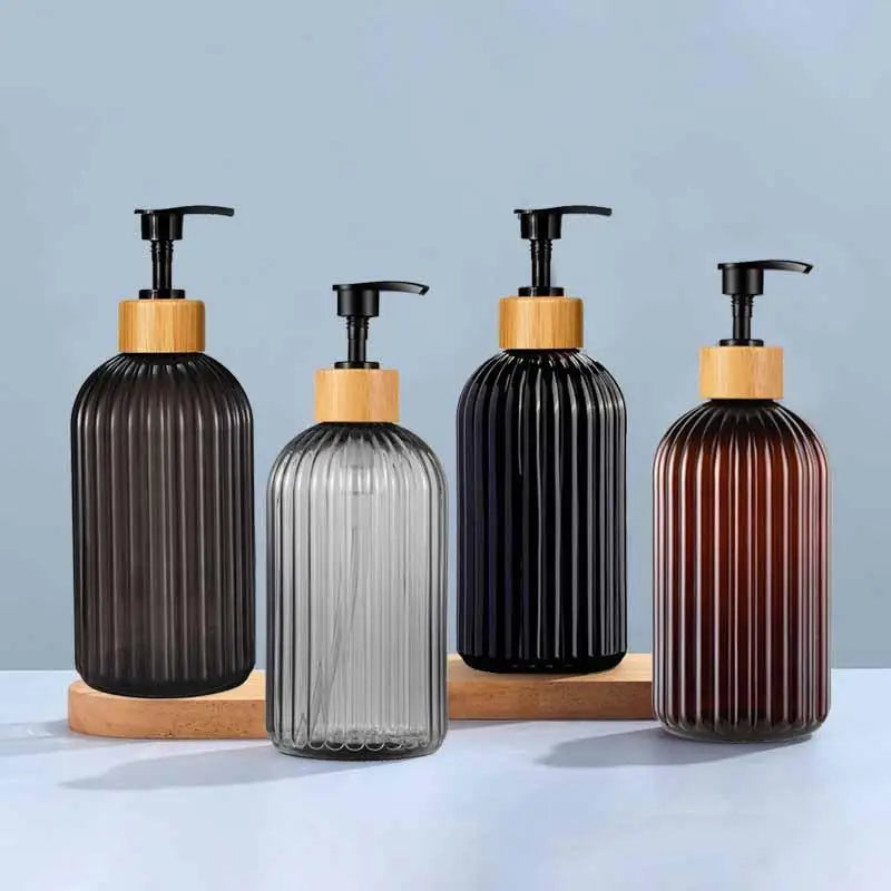 A set of two refillable soap dispensers with black glass bottles and wooden caps on a light blue surface.