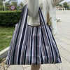 A black and white striped foldable oxford cloth tote bag carried by a person outdoors.
