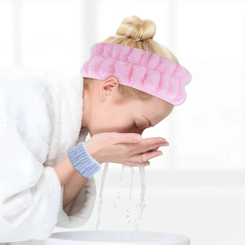 A person is using pink wrist washing bands to clean their face under running water.