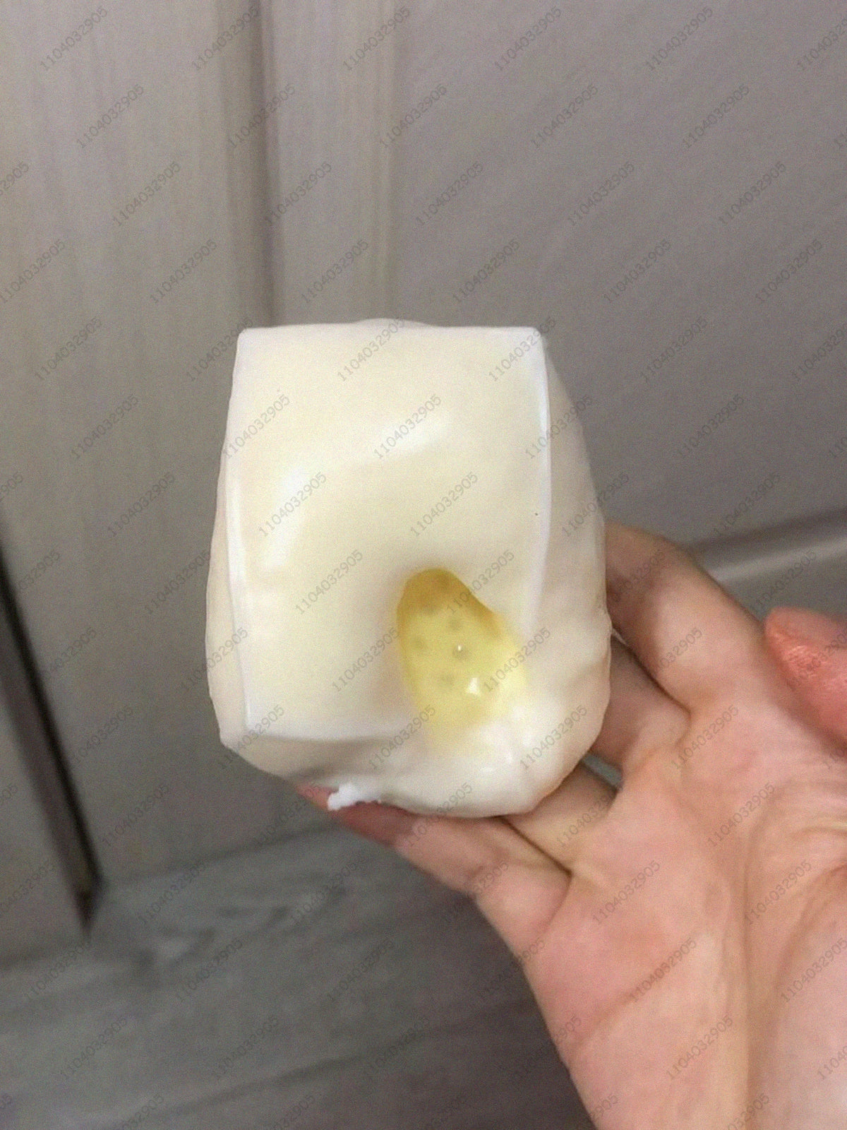 Eine weiße, weiche Kartoffel-Stressball mit gelbem Zentrum wird in der Hand einer Person gehalten.