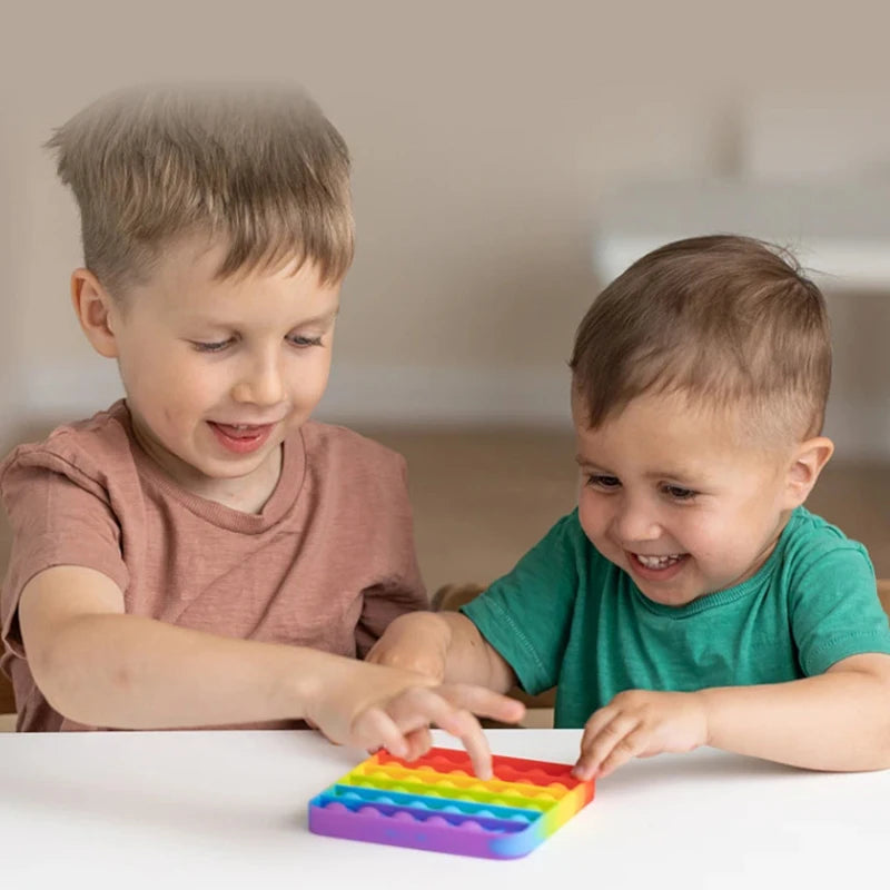 Two young children interact with a colorful 2-in-1 alphabet and number fidget toy.