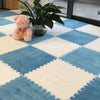 A soft pink plush rabbit sits on a blue and white diamond patterned rug next to a potted green plant.