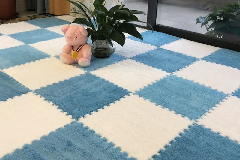 A soft pink plush rabbit sits on a blue and white diamond patterned rug next to a potted green plant.