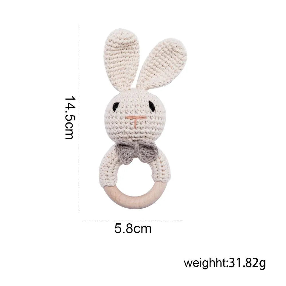 A handmade crochet bunny toy with long ears and a natural wood teether ring.