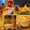 A golden, illuminated teepee tent decorated with string lights and flowers on a grassy lawn at night.