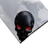 A black skull emblem badge with glowing red eyes is mounted on a clear, reflective surface.