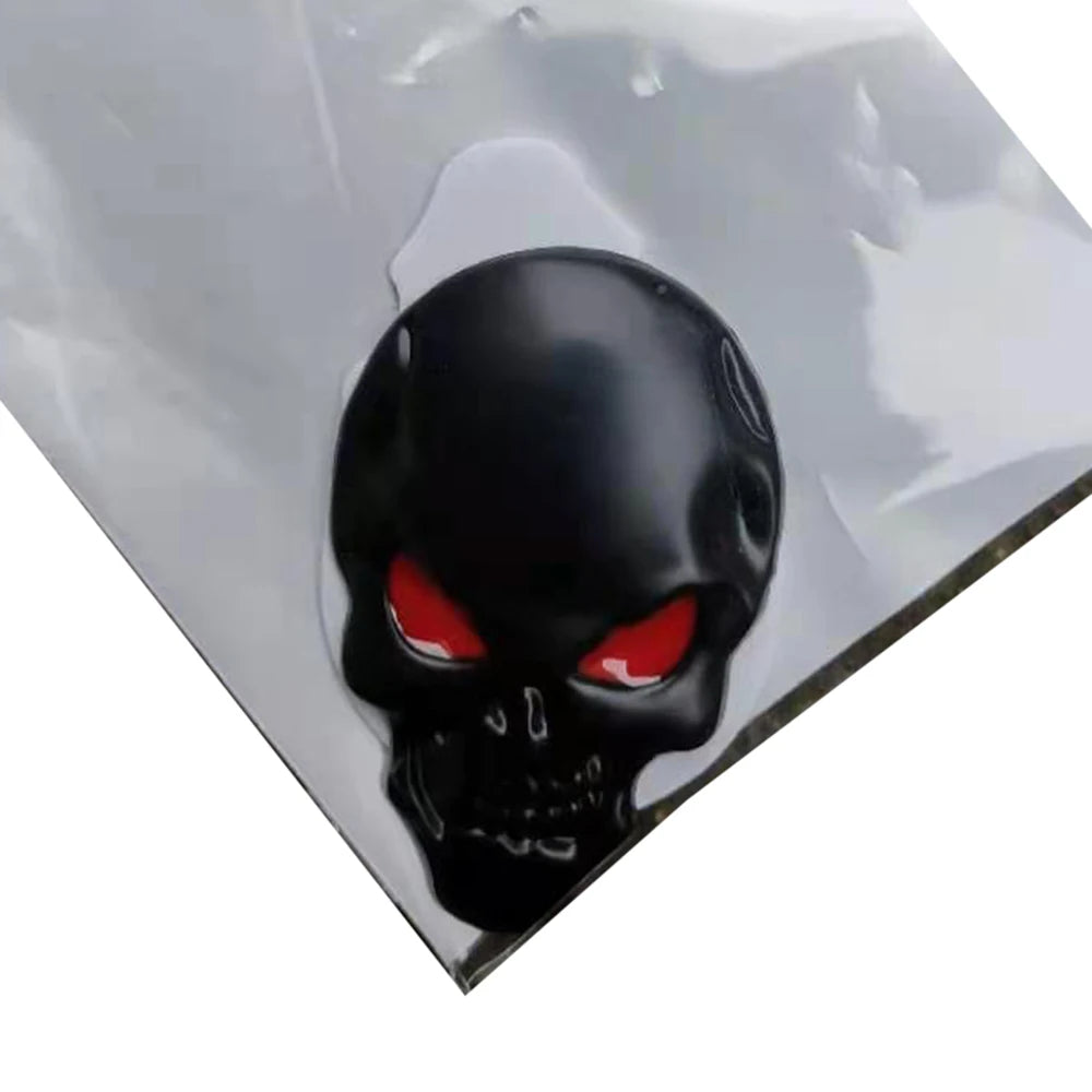A black skull emblem badge with glowing red eyes is mounted on a clear, reflective surface.