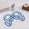 A blue and white towel shaped doormat with a bow design placed next to a silver figurine.