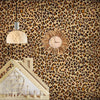 A wall decorated with leopard print wallpaper featuring a hanging light fixture and a wooden house structure.