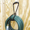 A coiled green heavy-duty hook and loop storage strap with a black handle hanging against a light wood background.