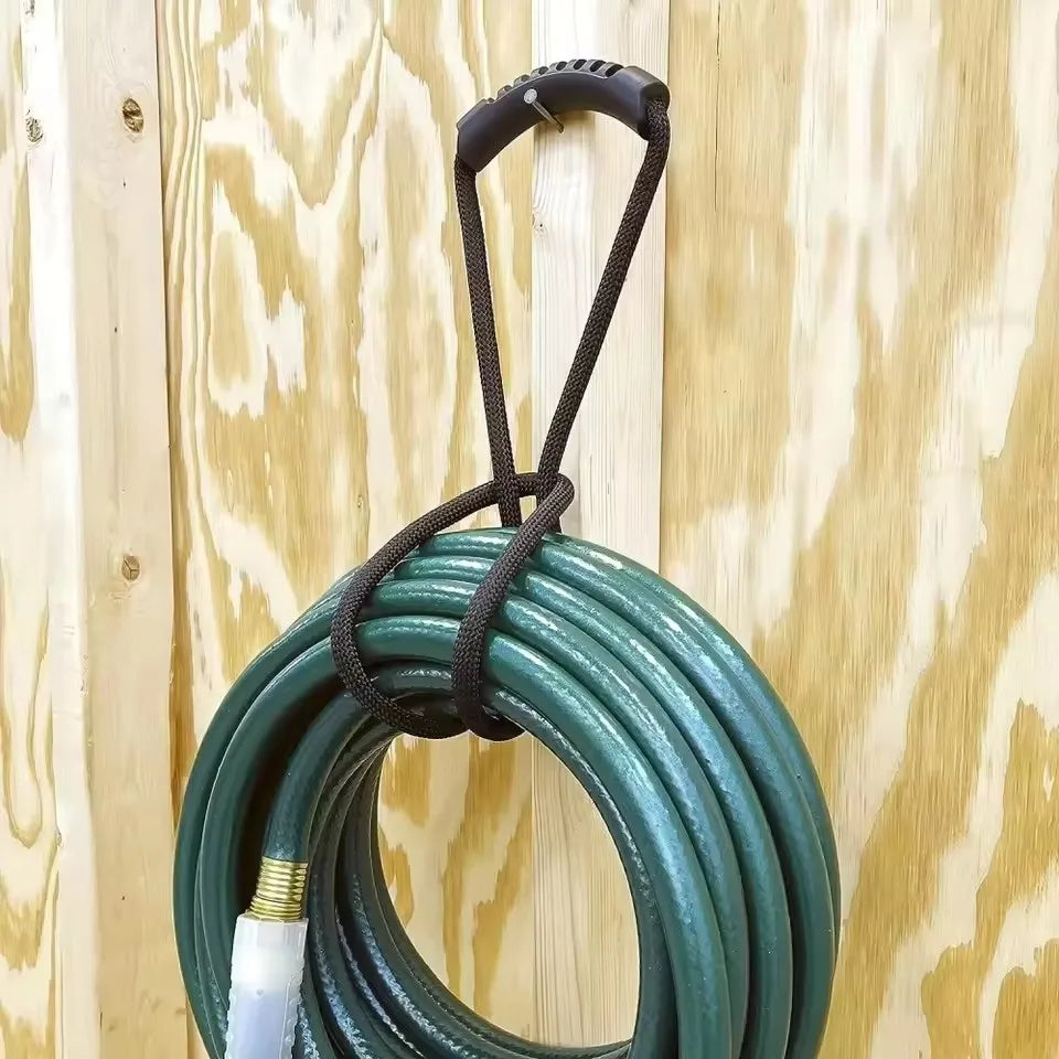 A coiled green heavy-duty hook and loop storage strap with a black handle hanging against a light wood background.