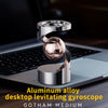 A silver aluminum alloy desktop levitating gyroscope spinning on a laptop surface.