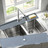 A silver faucet mat with a silicone design is placed in a kitchen sink under a window.