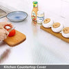 A kitchen countertop covered with aluminum foil peel-and-stick backsplash wall stickers and various kitchen items.