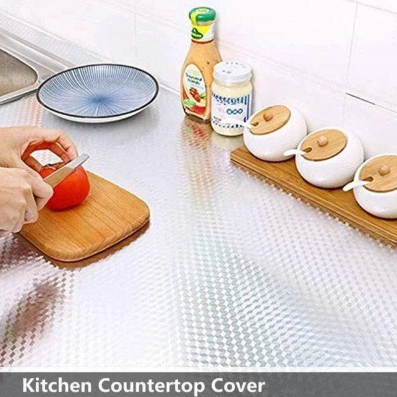 A kitchen countertop covered with aluminum foil peel-and-stick backsplash wall stickers and various kitchen items.