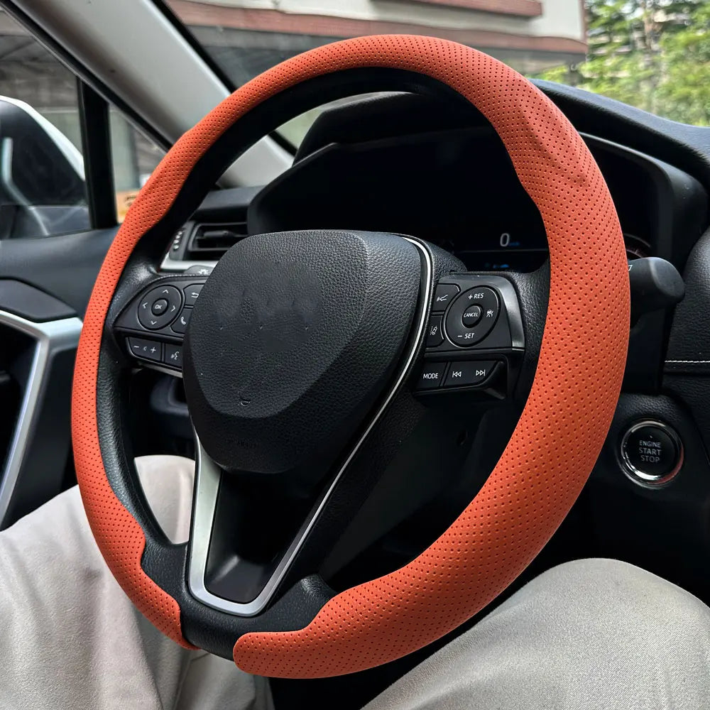 Close-up view of a black steering wheel with an orange breathable leather cover installed in a car interior.