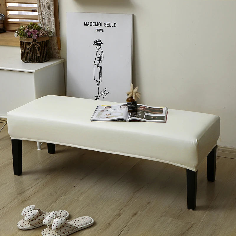 A white waterproof PU stretch bench cover is displayed on a wooden floor next to a framed illustration.