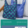 A dark blue shopping bag with a star pattern is shown next to a light gray surface, highlighting its foldability and material