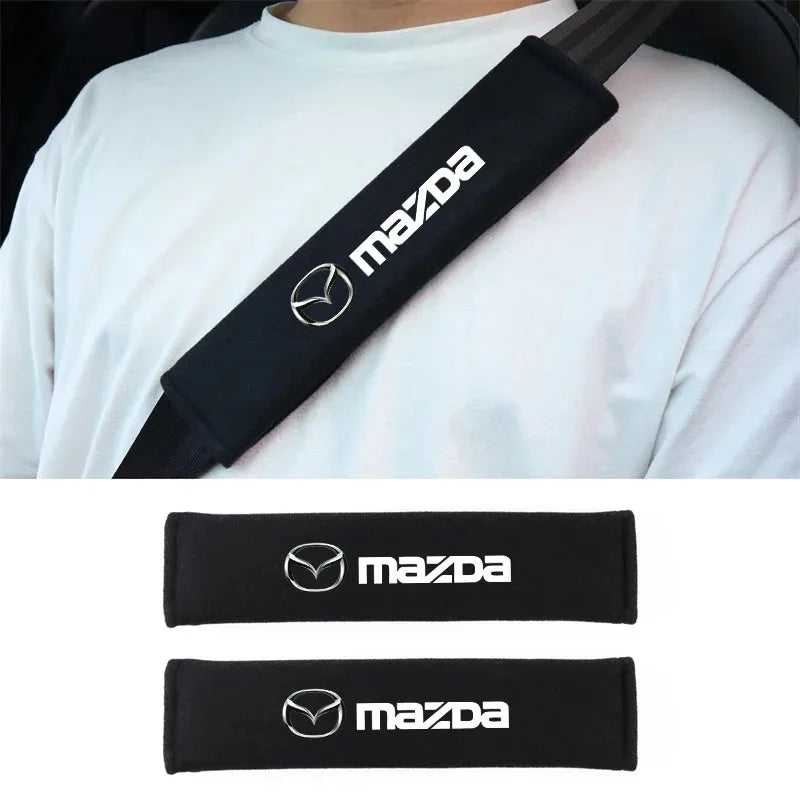 Black Mazda car seat belt shoulder protector cover shown on a white shirt.