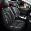 Interior view of a car showing black leather seats with quilted stitching and a patterned floor mat.