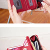 A close-up of a red leather wallet with a zipper closure being held by a hand.