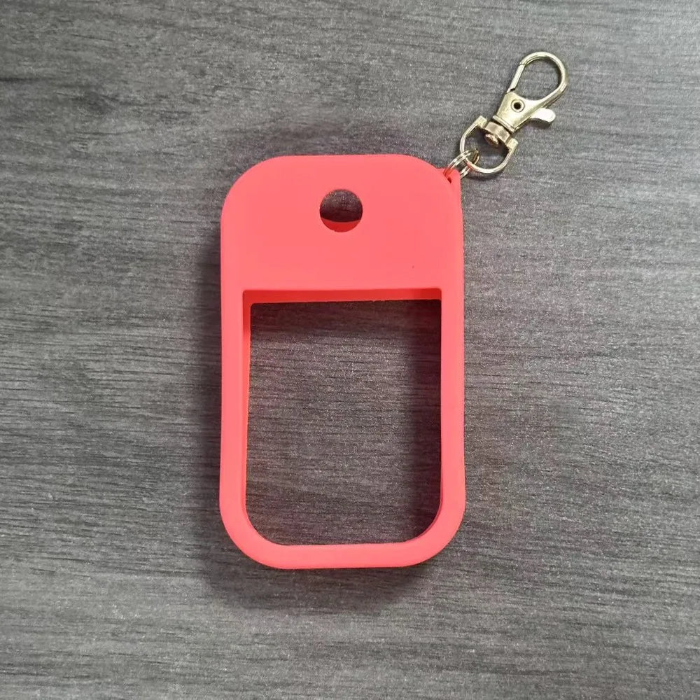 A bright pink silicone protective case for a hand sanitizer spray attached to a metal keyring.