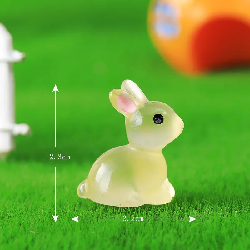A small, translucent yellow resin miniature bunny figurine sitting on green grass.