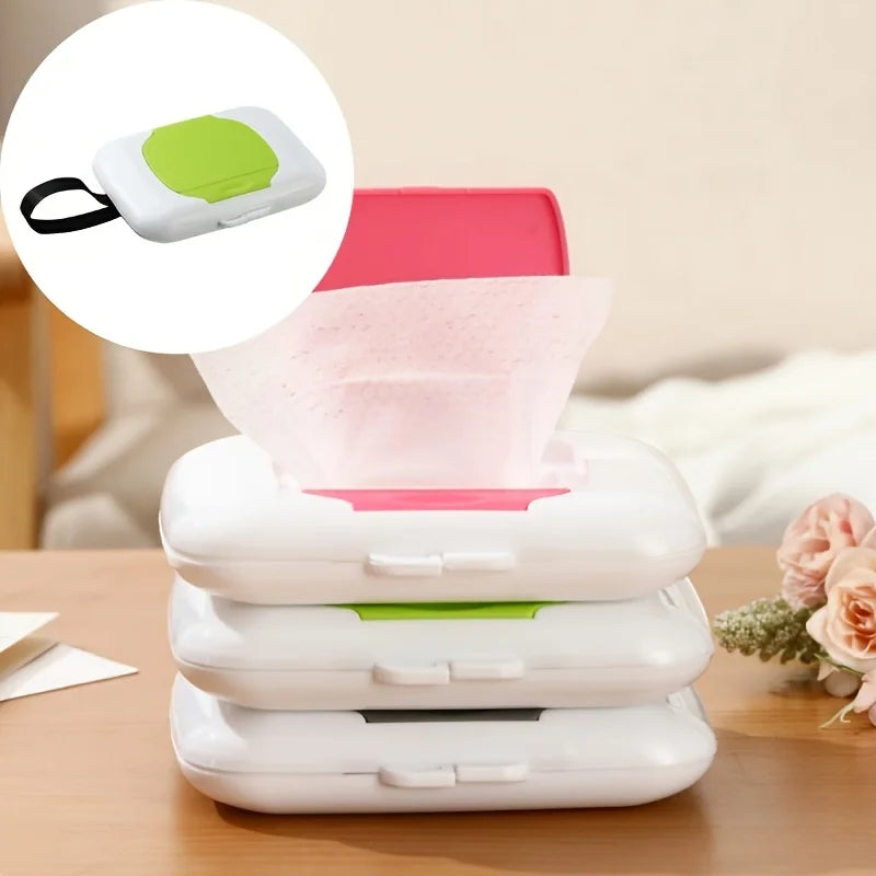 A stack of white refillable wipe dispensers with lime green accents and a pink wipe container on a wooden surface.