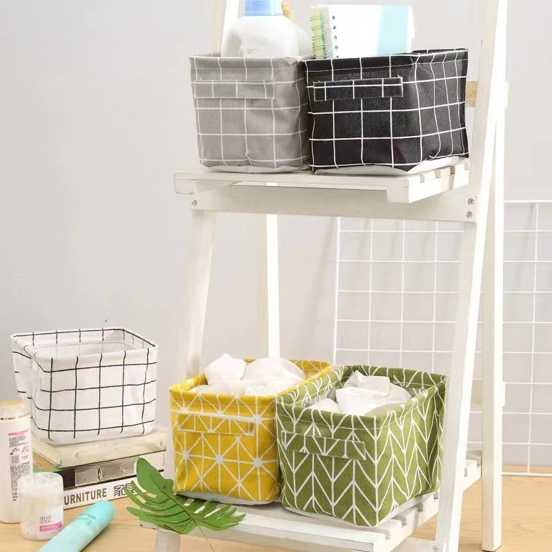 A white wooden shelf displaying various storage baskets made of cotton and linen fabric in black, gray, and lime green patter