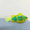 A yellow and teal light-up sensor swimming fish toy resting on a gray surface.