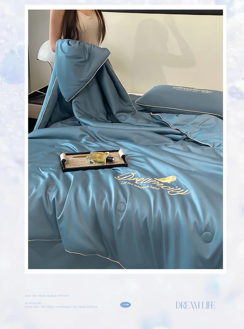 A teal ultra-soft cooling comforter is displayed on a bed, featuring embroidered text and a folded cover.
