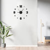 A black analog wall clock with a white face and black numbers is mounted on a white wall.