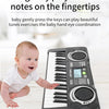 A baby is playing a small electronic piano with a microphone and LED display on a wooden surface.