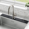 A modern stainless steel faucet mounted on a black absorbent stone tray above a kitchen sink.