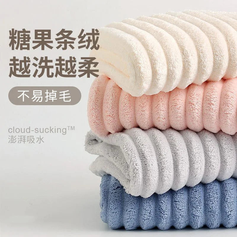 A stack of fluffy microfiber towels in various pastel colors, including pink, cream, gray, and blue.