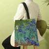 A canvas tote bag featuring a vibrant painting of blue and green flowers in the style of Van Gogh, carried by a person.