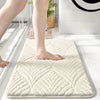 A beige plush velvet bathroom mat with a diamond pattern is shown on a white floor.