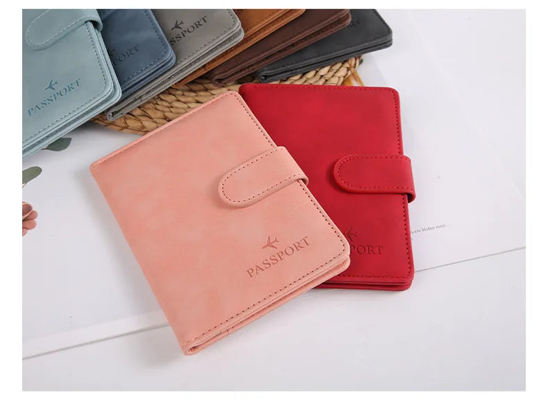 Un porte-passeport en cuir rose est montré à côté d'un rouge et de plusieurs autres porte-passeports sur une surface blanche.