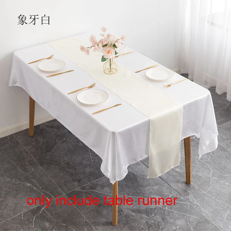 Elegant white satin table runner set with plates and a floral centerpiece on a white tablecloth
