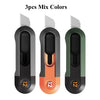 Trois petits couteaux utilitaires compacts de couleurs différentes : noir, orange et vert, montrés côte à côte