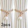 A set of two pearl and rope curtain tie-backs with gold accents shown against a light fabric background.