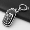 A silver Honda key fob is attached to a chain and placed on a black fabric surface.