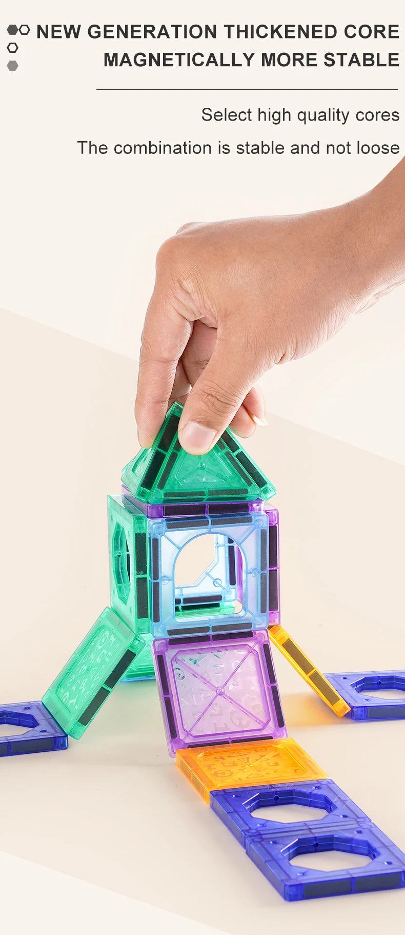 A hand is assembling a colorful magnetic building tile structure made of green, blue, and purple pieces.