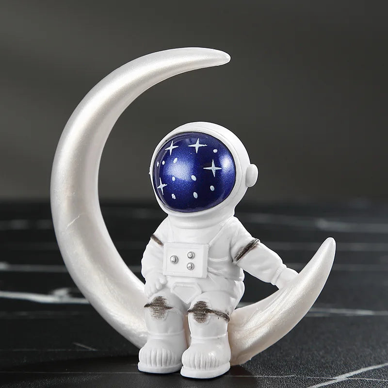A white astronaut figurine with a blue helmet and stars, sitting on a curved silver base.