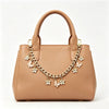 A tan leather handbag with a top handle and decorative gold chain featuring small flower charms.