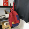 A red and blue canvas patchwork backpack hanging on a shelf next to a Coca-Cola sign.