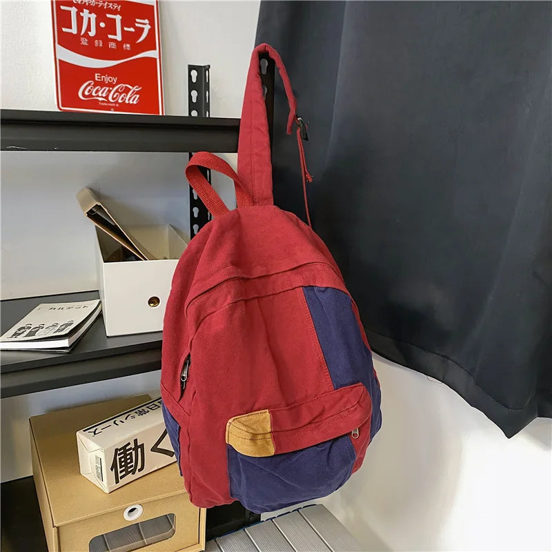 A red and blue canvas patchwork backpack hanging on a shelf next to a Coca-Cola sign.