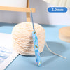 A spool of light pink yarn with a blue bee-themed crochet hook visible on the thread.