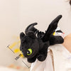 A black soft plush dragon toy resembling a Night Fury with green eyes, shown against a light background.